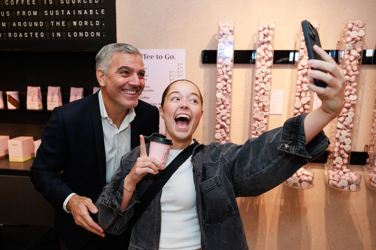 A George Clooney lookalike takes a selfish with a customer at the opening party for Grind's newest coffee store