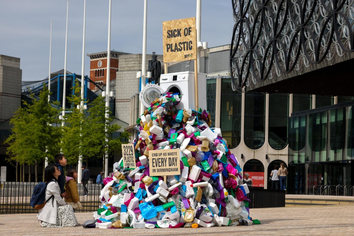 A large sculpture depicting a washing machine vomiting thousands of pieces of laundry plastic has been unveiled in Birmingham.