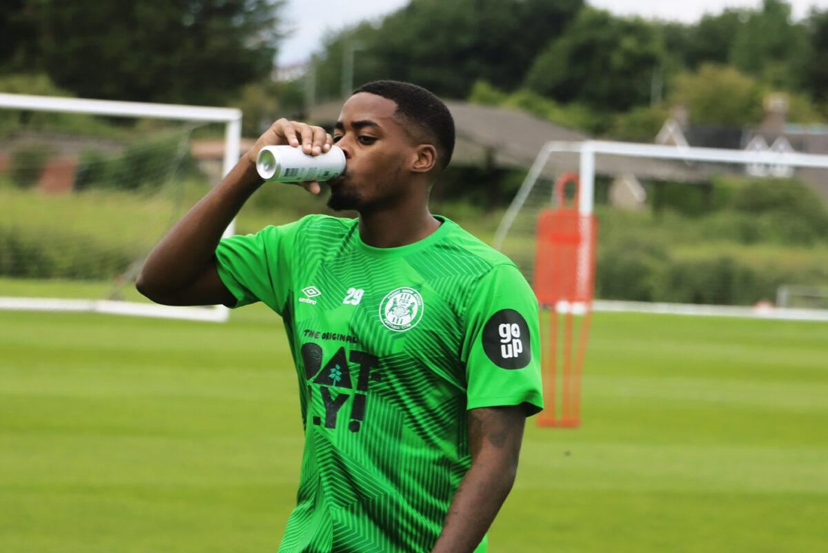 Forest Green Rovers FC has partnered with digital marketing agency Go Up for the third year to deliver the next saga of their commitment to sustainable development, a club player depicted here in a sponsored football shirt drinking from a metal can.