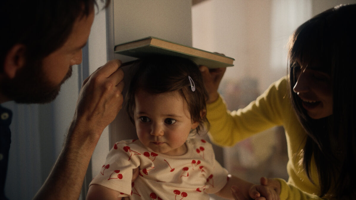 Savills has teamed up with its creative agency adam&eveDDB to unveil a heartfelt TV advert that marks the start of a brand new campaign platform, here depicting a still from the video - a young toddler's height being measured by it's parents using a book and a wall.