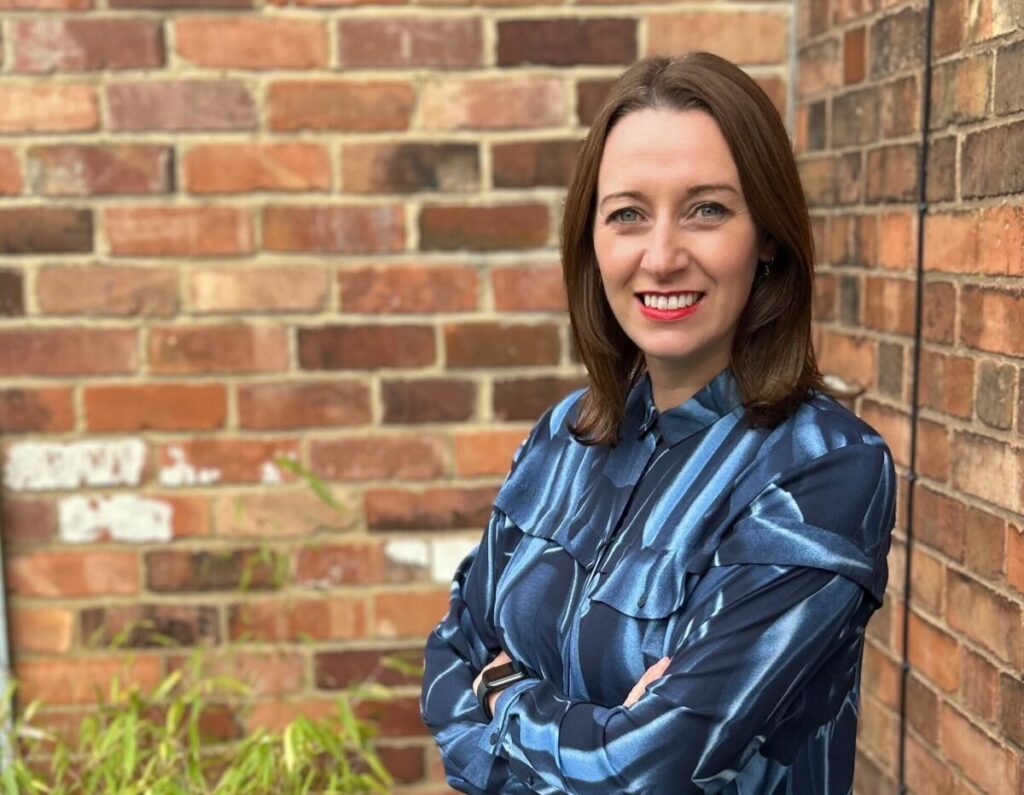 Marketing agency M&C Saatchi TALK has expanded its senior leadership team, announcing Hannah Wallace as its new business director., Wallace depicted here in a blue shift smiling against a brick background