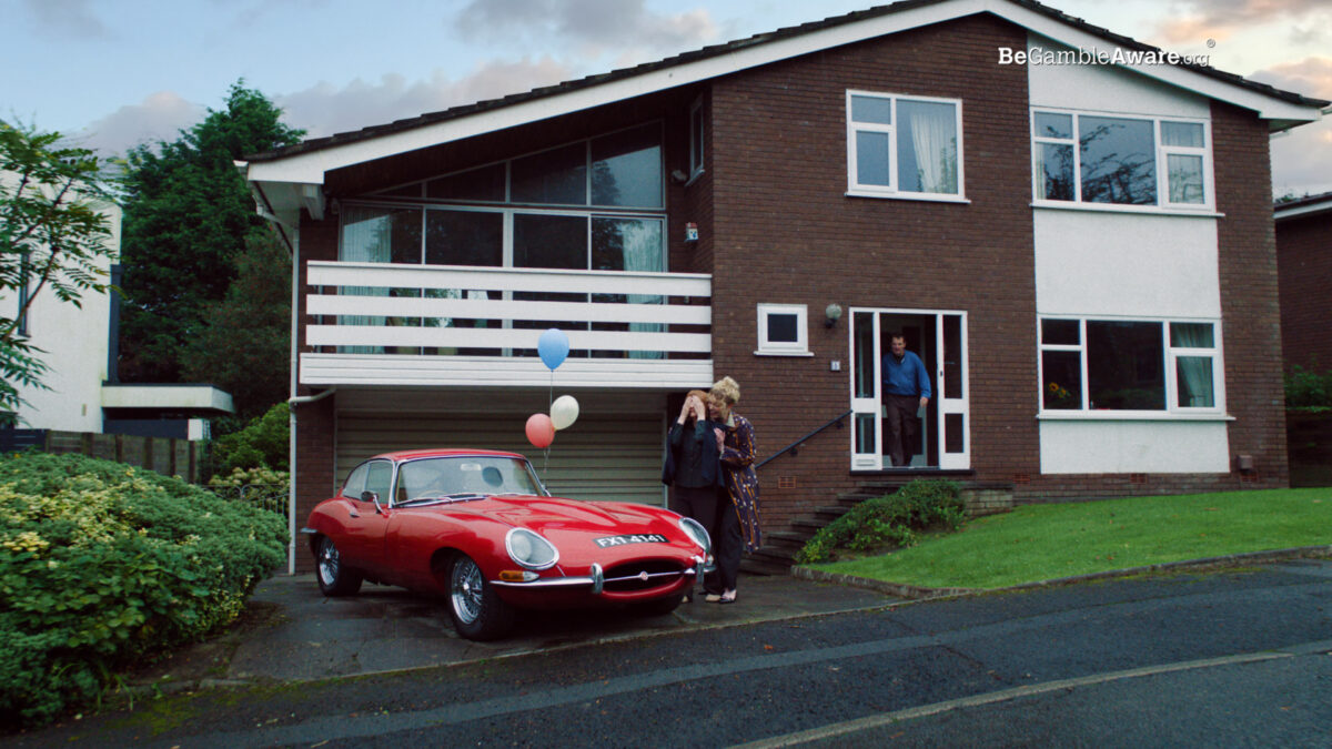 The People's Postcode Lottery is targeting new audiences with a mammoth campaign marking its most significant Q4 media spend to date., here depicting a house with a new vintage red car outside, complete with celebratory balloons