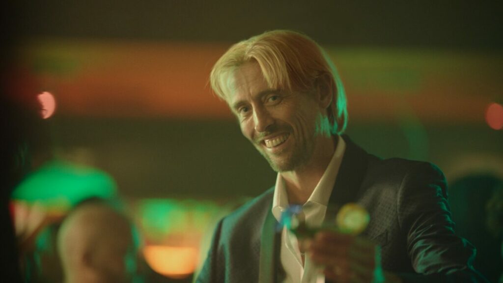 Paddy Power Games is reimagining a "Life with more chances" in its latest ad, giving viewers a glimpse of a reality with alternative scenarios, here depicting Peter Crouch in a blonde wig and in a bar setting
