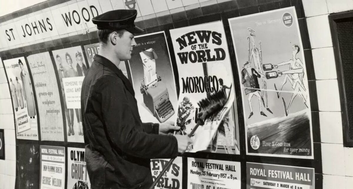 Transport for London's (TfL) poster exhibition look back at the network's early history of posters - from political advertising to brand commissions, here depicting a vintage photo of a TfL worker hanging poster's within the network