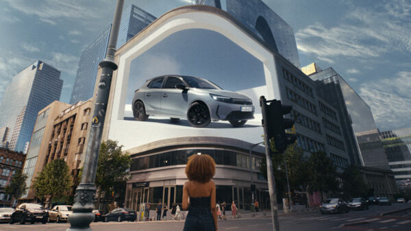 Opel is convincing hesitant buyers wanting to switch to a fully electric car that it is "Yes, of Corsa" the perfect car brand for you, here showing a young woman looking at a giant DOOH of the electric car