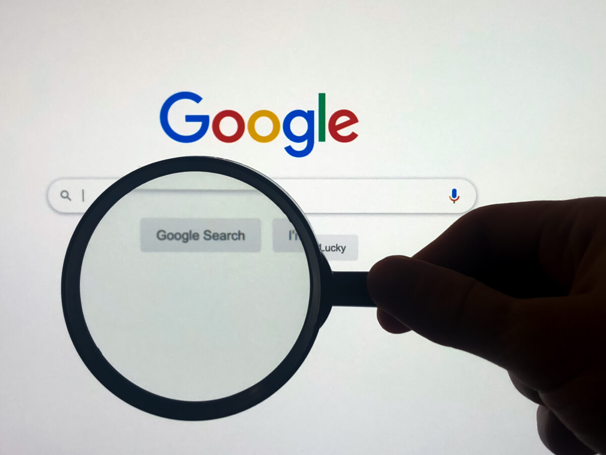 Google search engine with magnifying glass, illustrating that Google has run hundreds of adverts on hundreds of questionable sites, including those that play host to pornographic, zoophilic and pirated content.