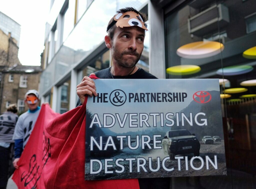 Campaigners protest outside The&Partnership offices with placades against the sale of SUVs, some dressed as animals as if killed by the vehicles. It follows the ASA Toyota ruling.