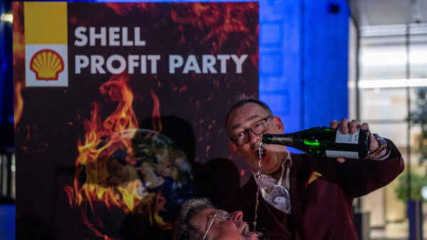 Greenpeace activists disguised as Shell executives drink champagne and dance around a burning sign reading ‘Your Future’ at a mock party outside the Shell