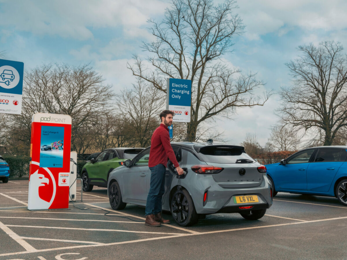 Man charging Vauxhall EV vehicle. Tesco partners with Vauxhall for EV advertising push across retail media