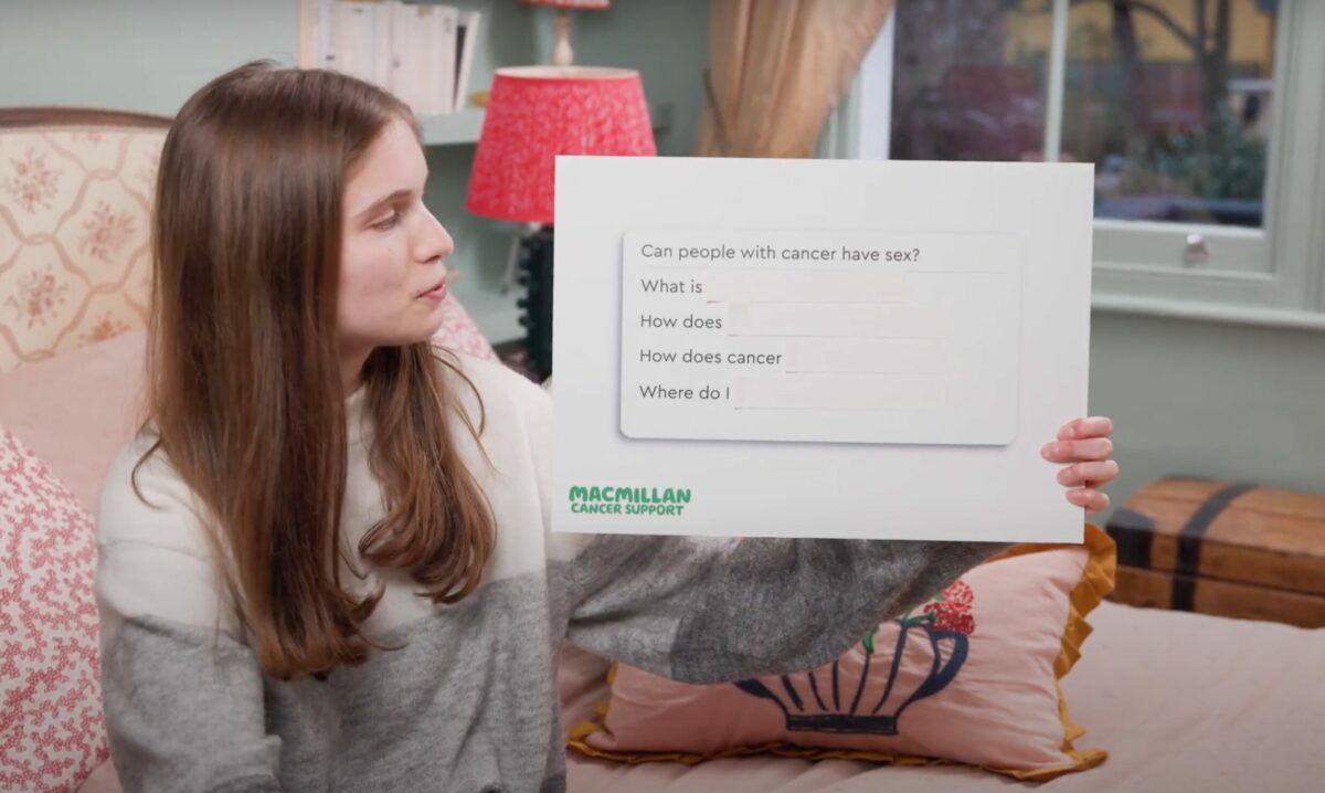 Image from the campaign showing Ellie holding a board with questions about cancer and sex. Macmillan and sexual wellness brand Lovehoney have partnered in order to break down taboos around sex and intimacy following a cancer diagnosis.