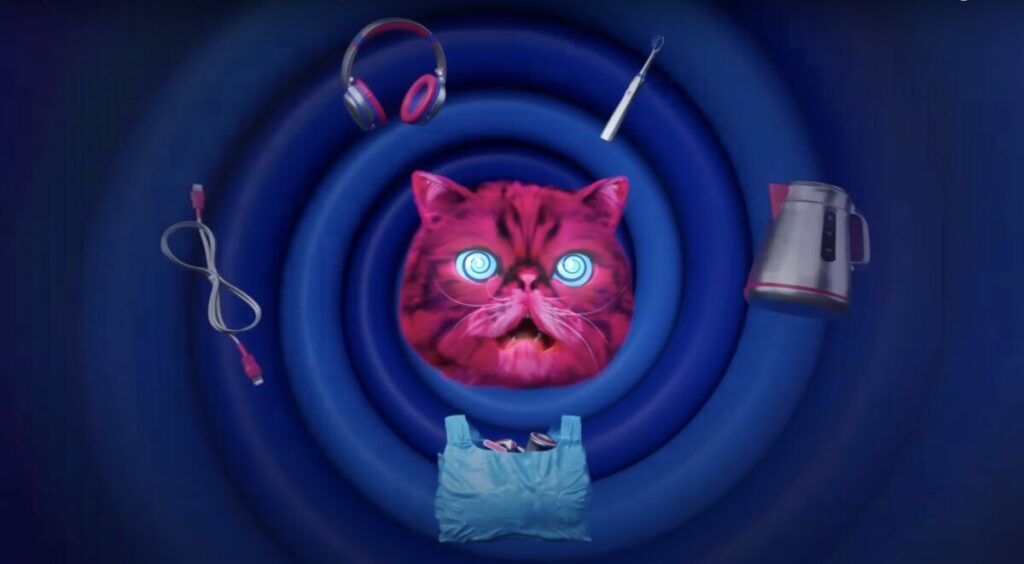 Image of Hypnocat surrounded by electricals in a swirly hypnotic style image. A fluffy pink mascot, designed to hypnotise people into recycling their electrical goods, is making a return to television screens.