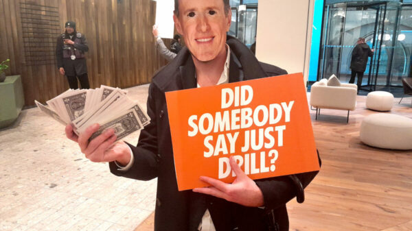 Activist holding "Did somebody say just drill" sign in McCann Worldgroup London HQ. A team of Extinction Rebellion activists infiltrated the London HQ of McCann Worldgroup, in protest about the company's link with Saudi Aramco.