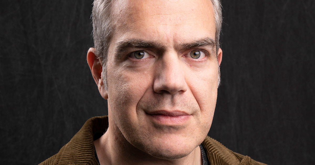 Antonis Kocheilas wearing a brown courderoy suit against a black background. Source: Ogilvy