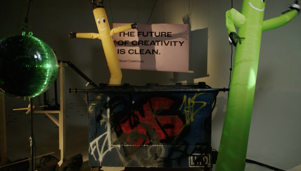 Still from Clean Creatives campaign video, a humorous inflatable figures is next to a sign which reads "The future of creativity is clean". Campaign group Clean Creatives has signed 1,000 agencies to its pledge to stop working with fossil fuel polluters.