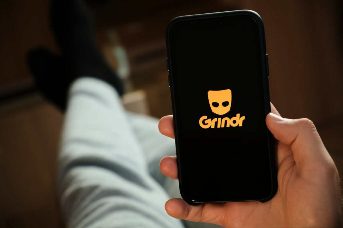 A person using Grindr on a mobile phone, they are lounging. A London lawsuit is to claim that Grindr shared personal information, including the HIV status of users, with ad firms.