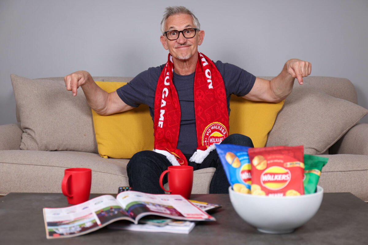 Crisp brand Walkers is giving football fans the chance to watch the sold out UEFA Champion's League final in a VIP box at Wembley with Gary Lineker. The image shows Gary Lineker sat at home on a sofa with a Walkers scarf around his neck. He is smiling, surround by magazines cups of tea and of course a bowl of Walkers.