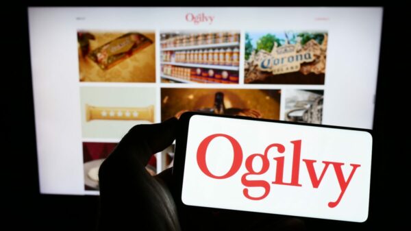 Ogilvy branding and imagery, a person is holding a phone that reads ogilvy in front of a computer on which Ogilvy has also been searched. Ogilvy has appointed it first global chief transformation officer, Antonis Kocheilas, who is tasked with identifying