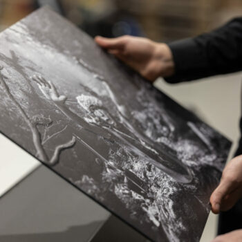 Image of a person interacting with the tactile 3D printed image of 'Prayer to the Yanomani Goddess' by renowned photographer Sebastiao Salgado, which depicts a deeply focused shaman, with his arms outstretched praying to his goddess in the mountains.