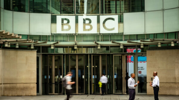 Workers stand outside the BBC building. A group of 20 media businesses have written to the government, expressing concern about the BBC's plans to introduce ads on audio content.