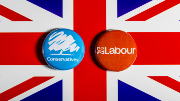 A British flag with Labour and Conservative badges side by side placed on top. Labour has been spending almost three times more than the Conservatives on advertising, in the days following the 4 July election announcement.