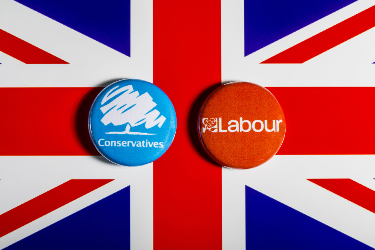 A British flag with Labour and Conservative badges side by side placed on top. Labour has been spending almost three times more than the Conservatives on advertising, in the days following the 4 July election announcement.