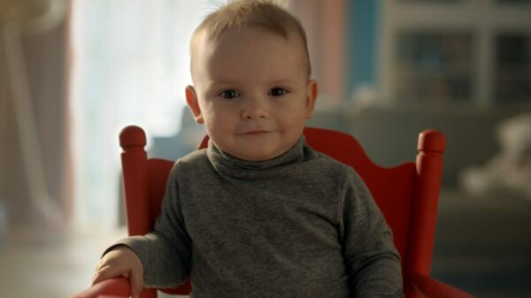 Sudocrem baby wearing a grey jumper on a red chair sits with a smirk and a concentrated face ready to explain the product...Sudocrem has unveiled its first ever unified ad campaign, which expands the brands focus from babies to the entire family by using a baby as a spokesperson.