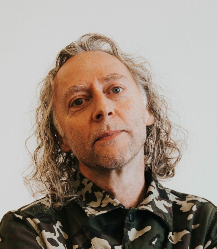 John Mescall wearing a camouflague shirt and tilting his head. Former president of McCann's global community John Mescall, is joining by The Network as creative chair.