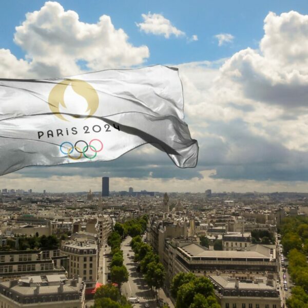 Olympic flag flies above a cloudy Paris. Badvertising finds that sponsorship deals between four giants and the Olympics amount to the same amount of emissions as eight coal plants.