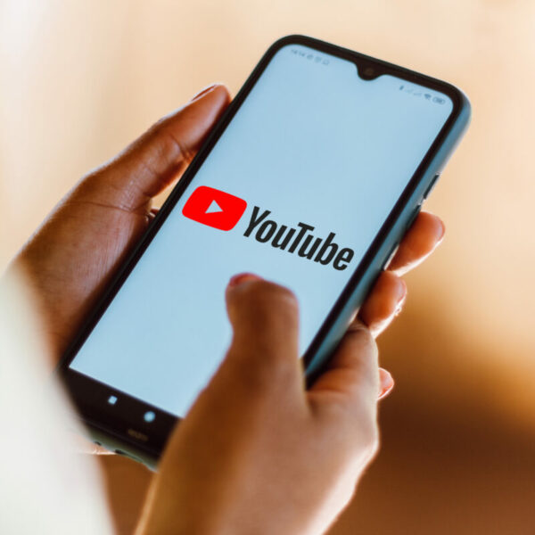 A person scrolls on their phone with Youtube in front of them. Youtube took to social media to highlight that the platform is serving them with blank ads or black screens before a video if they use an ad blocker.