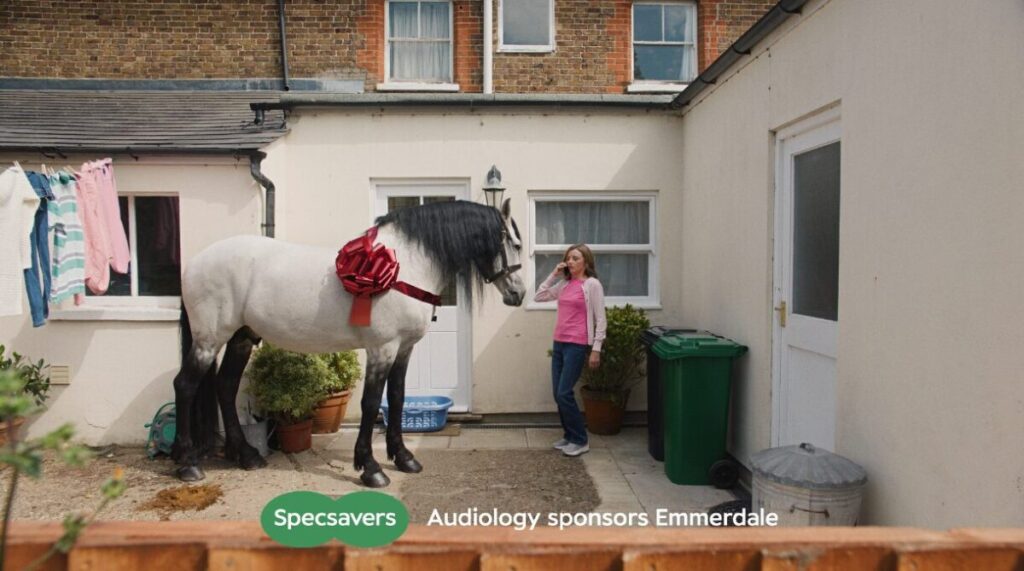 A horse stands outside a house and a lady stares at it. Specsavers is sponsoring iconic prime-time soap opera Emmerdale with a unique series of humorous, drama-filled idents for the show's audience.
