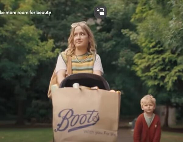 Screenshot from Boots adverts showing a mother pushing a pushchair with a bag full of Boots products. Boots newest advert spotlights its expanded range of beauty brands including Made by Mitchell, The Beauty Crop and Tree Hut, with skincare icons including Laneige, Supergoop! and Beauty of Joseon.