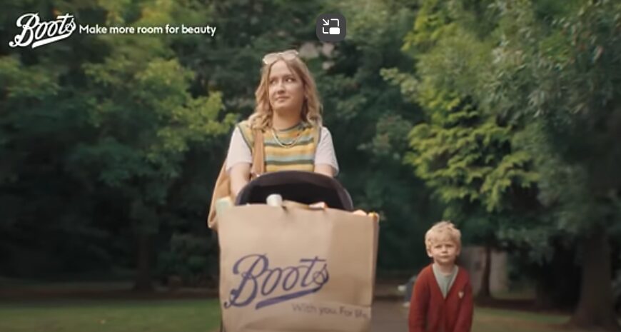 Screenshot from Boots adverts showing a mother pushing a pushchair with a bag full of Boots products. Boots newest advert spotlights its expanded range of beauty brands including Made by Mitchell, The Beauty Crop and Tree Hut, with skincare icons including Laneige, Supergoop! and Beauty of Joseon.