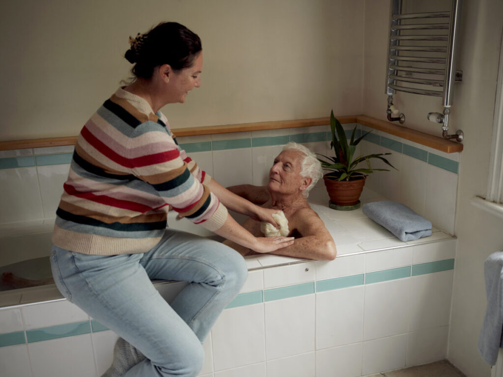 A woman shown helping her elderly father to bathe. Mullenlowe have created the campaign comes after winning The Creative Shootout 2024 competition to work with Carers UK.
