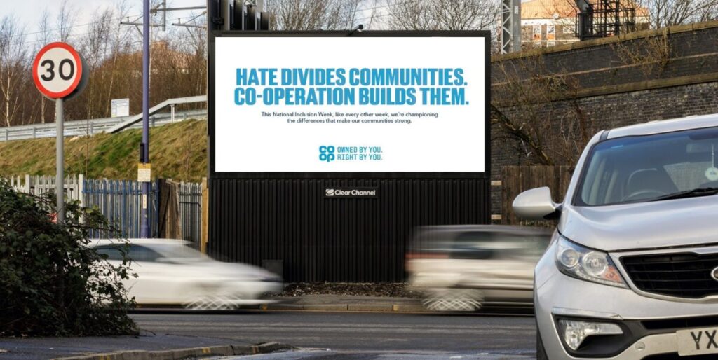 A Co-op billboard reads Hate divides communities. Co-operation builds them. Co-op is showcasing its work with community causes in a bold new out-of-home campaign created to mark National Inclusion Week. 