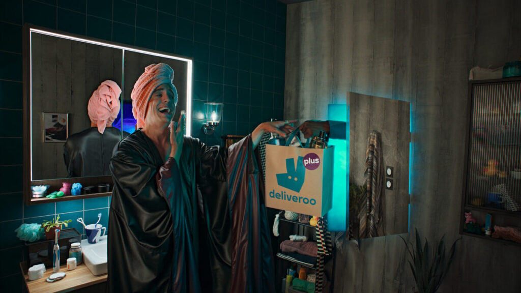 Villainous character laughs as hey hold up a deliveroo bag while getting ready for the evening ahead dressed in a long black cloak and a pink head towel. Food delivery company Deliveroo has partnered with its agency of record Pablo to create a new brand platform to highlight its new loyalty offering.